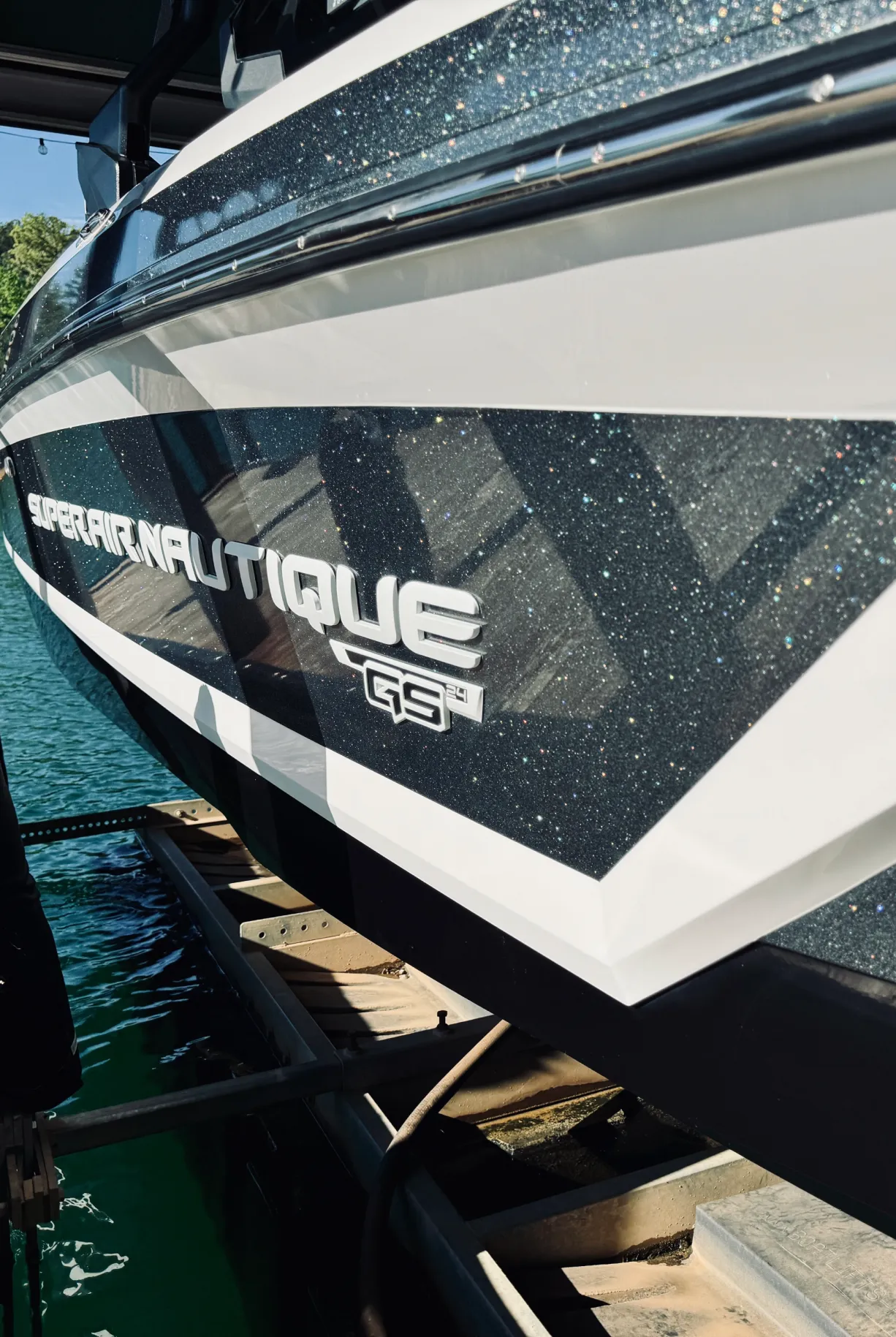 Close-up of a Super Air Nautique G21 boat side, with water and dock visible below.