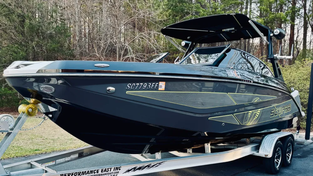 gallery-11 A black Starcraft speedboat on a trailer, parked outdoors with trees in the background.