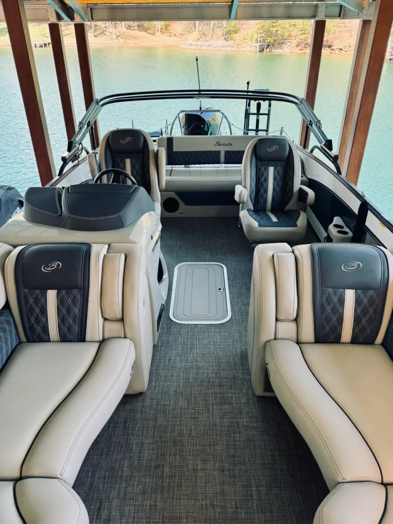 gallery-17 Interior of a pontoon boat with gray and cream seats under a wooden canopy, docked by the water.