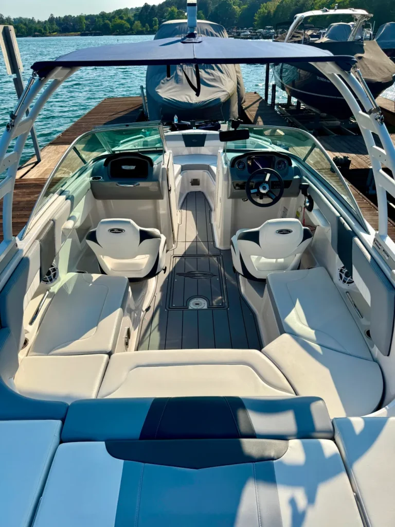 gallery-22 Open bow motorboat with white seats, steering wheel, and dock in the background on a sunny day.