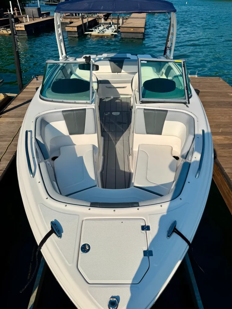 gallery-24 White and gray motorboat docked on clear blue water, with open windshield and seating visible.