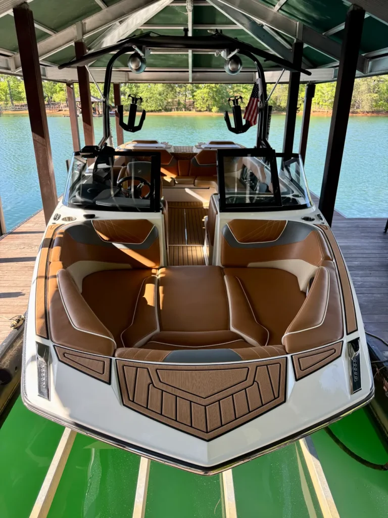 gallery-27 A modern speedboat with brown seats docked under a covered boathouse on a sunny lake.