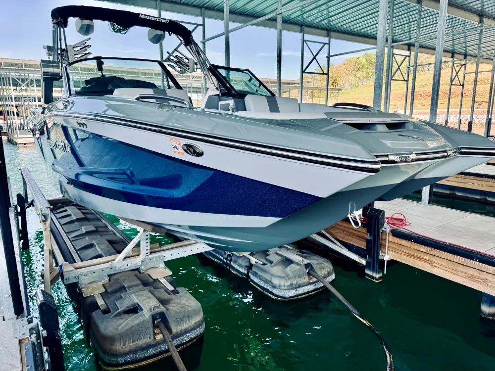 gallery-3 Blue and white speedboat on a lift in a covered marina, with green water and docks nearby.