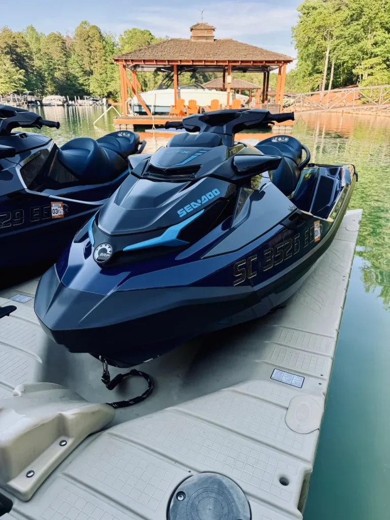 gallery-31 Black Sea-Doo jet ski docked on a floating platform by clear water, gazebo and trees in the background.