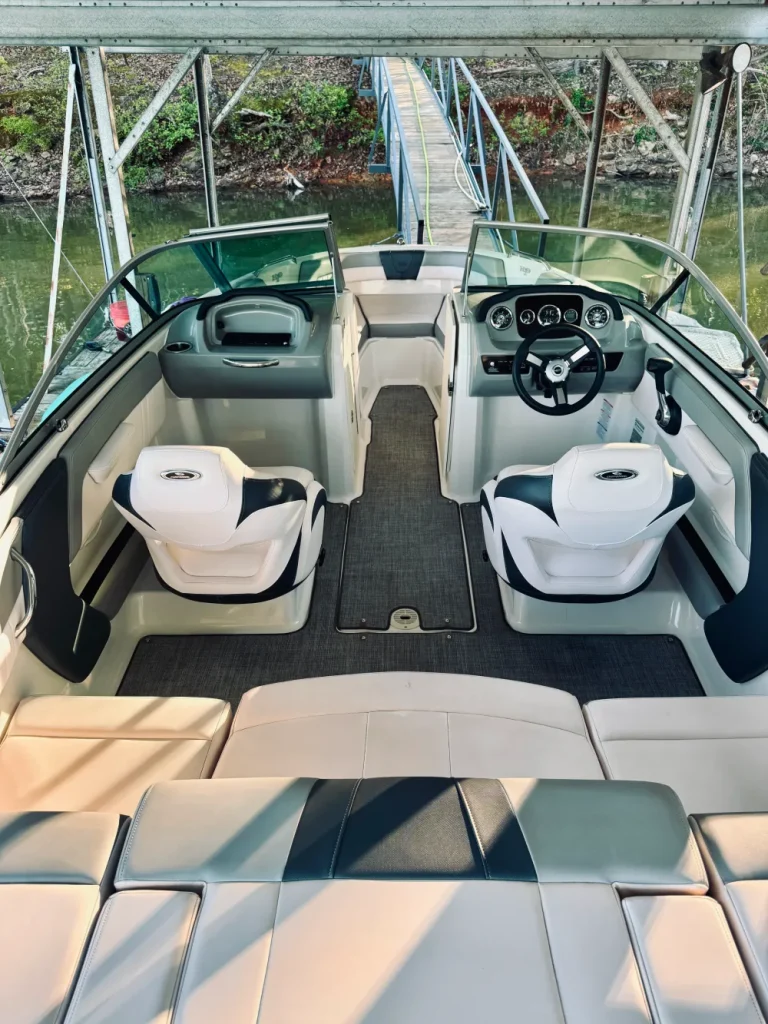 gallery-42 Empty white and black boat interior docked at a pier, showing seats, controls, and a walkway to shore.