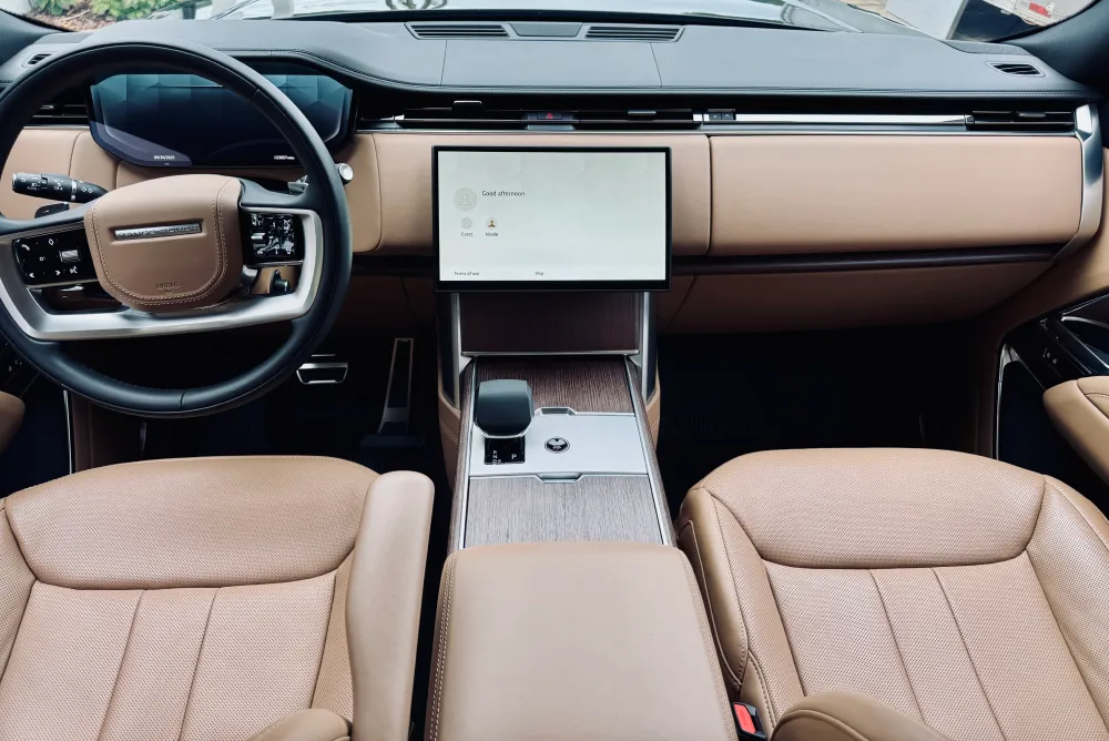 gallery-52 Modern car interior with tan leather seats, digital dashboard, and large touchscreen center display.